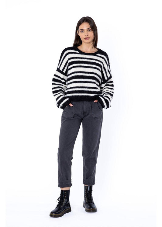 Woman wearing a striped sweater and dark trousers on a white background